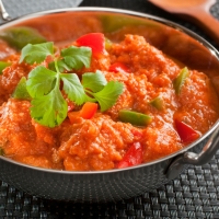 Indisches Chicken Jalfrezi mit Paprika und Tomaten, serviert in schwarzer Schale – India4U Bern