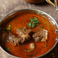 Aromatisches Lamm-Curry in einer kupfernen Schale mit Koriander garniert – India4U Bern