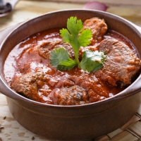 Traditionelles Lamb Rogan Josh mit zartem Lammfleisch in aromatischer Tomaten-Joghurt-Sauce – serviert bei India4U Bern