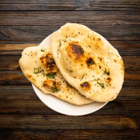 Tandoor‑gebackenes Fladenbrot mit frischem Knoblauch & Koriander.